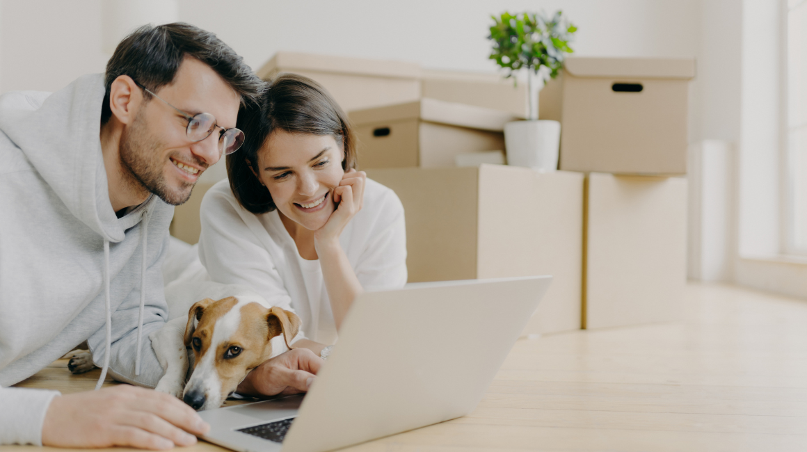 Młoda para z psem przegląda internet na tle kartonów przeprowadzkowych